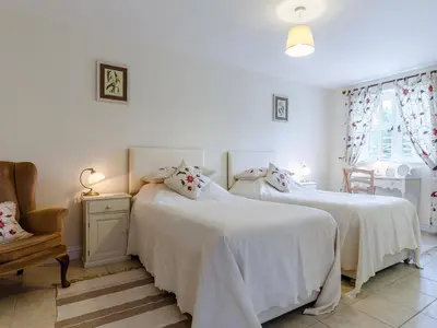 a bedroom with two beds with white sheets and a chair at 2 Bed in Truro oc-ljasm in Saint Allen