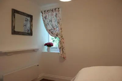 a bedroom with a window with a flower curtain at Lil' Nauti in Pentewan