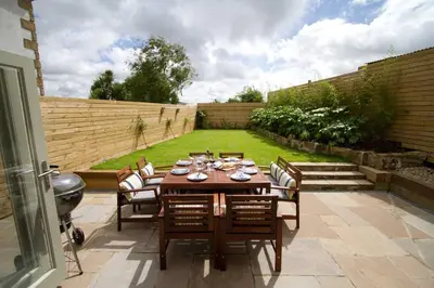 a wooden table and chairs in a garden at Barnwell Cottage *Stunning Cornish Cottage* Oozing Charm + Comfort in Cubert