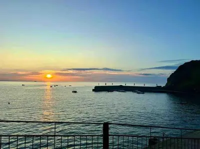 a sunset over a body of water with boats at Ebb Tide - Fisherman's Cottage in Gorran Haven