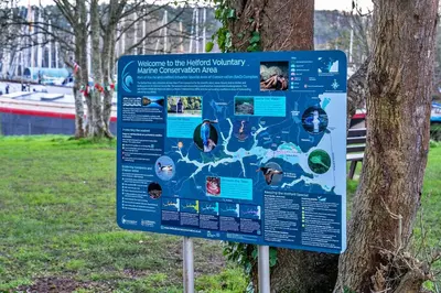 a sign in a park next to a tree at Finest Retreats - The Old Counting House in Gweek