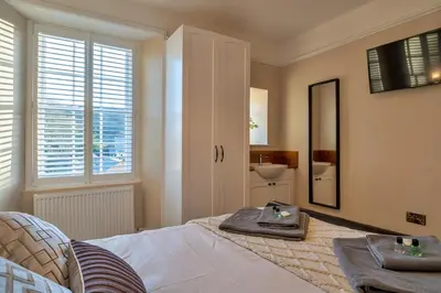 a bedroom with a bed and a mirror and a sink at Finest Retreats - The Old Counting House in Gweek