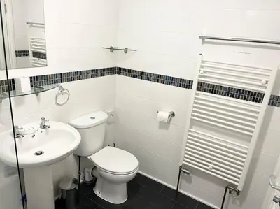 a white bathroom with a toilet and a sink at Seascape Stay No 4, Sea View & Parking in Falmouth