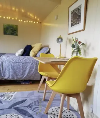 a room with a table and chairs and a bed at The Daffodil Hut in Porkellis