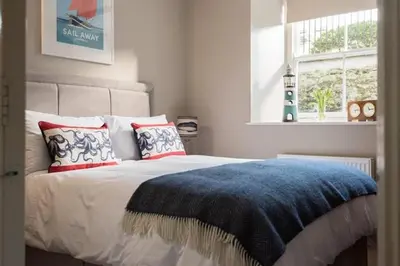 a bedroom with a bed with a blue blanket and a window at Stone's Throw - 2 Bed Apartment Centre of Falmouth in Falmouth