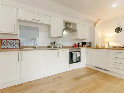 a white kitchen with white cabinets and wooden floors at 1 Bed in Callington oc-54344 in Linkinhorne