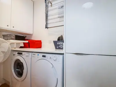 a laundry room with a washer and a white refrigerator at Towan Penthouse in Newquay