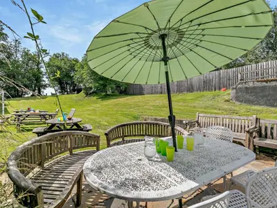 a table with a green umbrella on a patio at 2 Bed in Launceston oc-02036 in North Petherwin