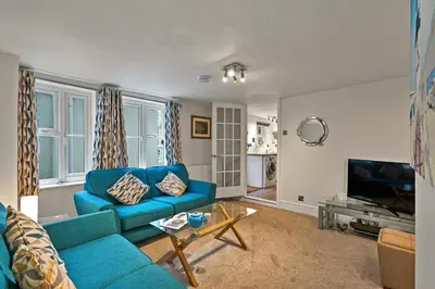 a living room with a blue couch and a tv at Finest Retreats - Porthole Cottage in Mevagissey