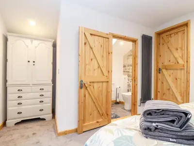 a bedroom with a bed and a wooden door at La Petit Maison in Saint Columb Major