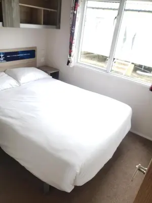 a white bed in a room with a window at Sea Break, Perran Sands, Perranporth in Perranporth