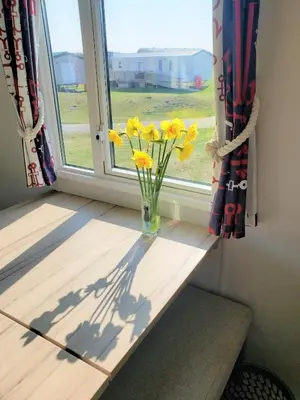 a vase of yellow flowers sitting on a window sill at Sea Break, Perran Sands, Perranporth in Perranporth