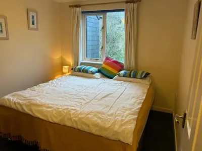 a bedroom with a large bed with a window at Creek Cottage in Budock Water