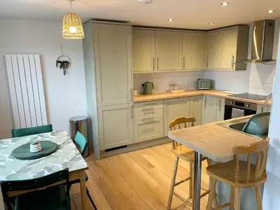 a kitchen with white cabinets and a table with chairs at Contemporary Holiday apartment in Perranporth