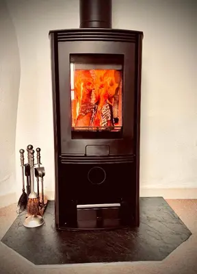 a fireplace with a fire inside of it at The Roundhouse Tregonce, Padstow, near the sea in St. Issey