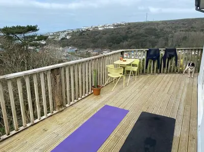 a dog standing on a deck with a table and chairs at Cliffside 3 Bedroom House with Sea Views in Portreath