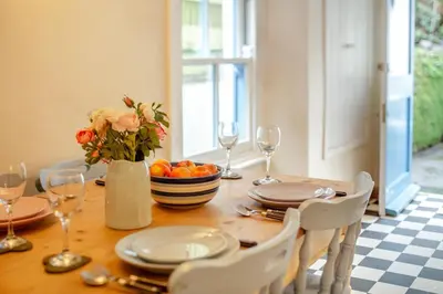 a dining room table with a vase of flowers and wine glasses at 2 Bed in Little Petherick oc-w28425 in Little Petherick