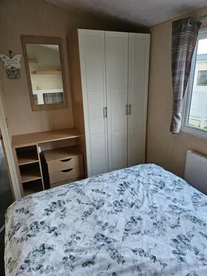 a bedroom with a bed and a dresser and a mirror at 113 Caravan at meadow lakes in St Austell