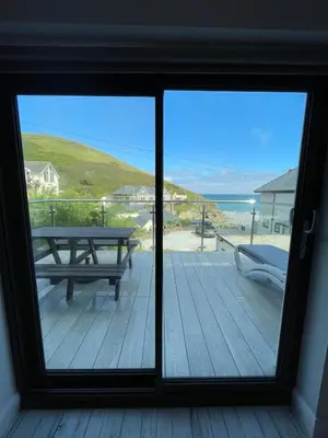 a view of a deck with a picnic table and the ocean at THE ANNEXE AT UPPER BEACH HOUSE in Portreath