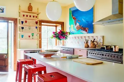 a kitchen with a white counter and red stools at Lostwithiel Manor in Braddock
