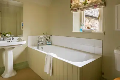 a bathroom with a large tub and a sink at Lostwithiel Stable House in Braddock