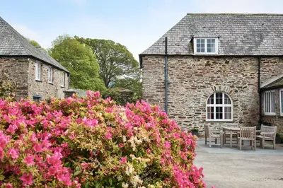 a stone house with pink flowers in front of it at Lostwithiel House in Braddock