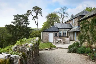 a stone house with a table and chairs in front of it at Lostwithiel Dairy House in Braddock