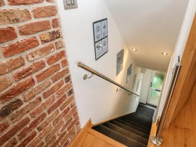 a hallway with a brick wall and a wooden door at Rooftops in St Ives