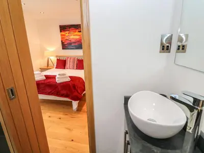 a bathroom with a sink and a bedroom at Rooftops in St Ives