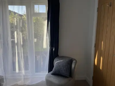 a chair with a pillow in front of a window at Porthkidney Suite, Carbis Bay, St Ives, free parking, near beach in Carbis Bay