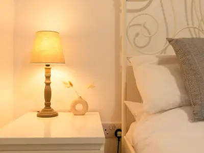 a lamp on a night stand next to a bed at Chalet Hot Tub Lodge 1 by Interhome in Helston