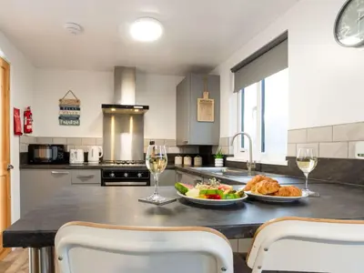 a kitchen with a table with a plate of food and wine glasses at Chalet Hot Tub Lodge 2 by Interhome in Helston