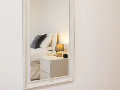 a mirror with a bed and a lamp on a nightstand at Chalet Hot Tub Lodge 2 by Interhome in Helston