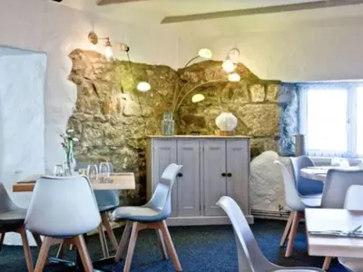 a room with tables and chairs and a stone wall at Chalet Hot Tub Lodge 3 by Interhome in Helston