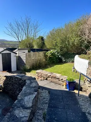 a garden with a stone wall and a bench at Little Hillside in Porthtowan