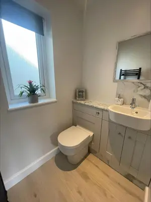 a bathroom with a toilet and a sink and a window at Bumblebee Barn, Luxury contemporary holiday home in Perranporth