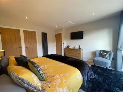 a bedroom with a large bed and a couch at Bumblebee Barn, Luxury contemporary holiday home in Perranporth