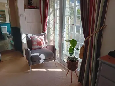 a chair sitting in front of a window with a plant at The Barn in Penzance