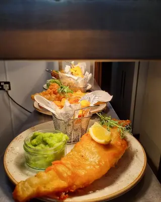 a plate of food with a piece of fish and chips at Two Bedroom Lodge In The Country - Restaurant Bar Onsite in Liskeard