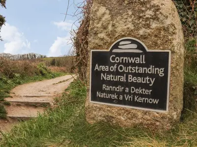 a sign on a rock next to a trail at Swans Nest in Falmouth