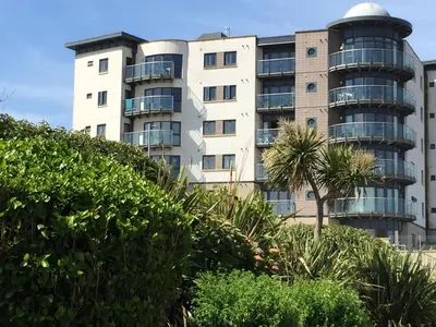 a building with a palm tree in front of it at 2Bed with Pool & Sea View Apartment in Newquay