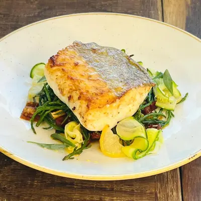 a plate of food with a piece of fish and vegetables at Halfway House Inn in Wadebridge