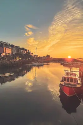 a boat is docked in the water at sunset at Holiday Home Stargazey Cottage by Interhome in Mevagissey