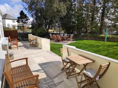a patio with chairs and tables and a lawn at Chandler's Lodge B&B in Camelford
