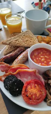a plate of breakfast food with sausage bread and salsa at Chandler's Lodge B&B in Camelford