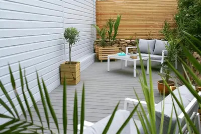 a patio with a bench and a table with plants at Scandi Cabin On A Hill, With Stunning Views Across Cornwall in Nancledra