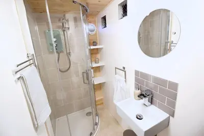 a bathroom with a shower and a sink and a mirror at Scandi Cabin On A Hill, With Stunning Views Across Cornwall in Nancledra