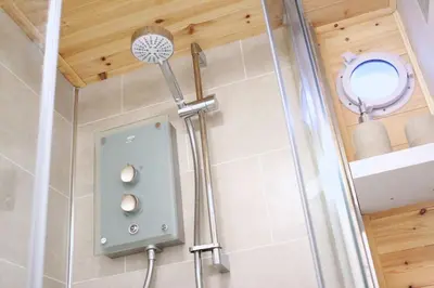 a shower in a bathroom with a glass door at Scandi Cabin On A Hill, With Stunning Views Across Cornwall in Nancledra