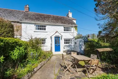 a white cottage with a table and a blue door at Blue Cottage - 3 bedroom cottage in Feock in Feock