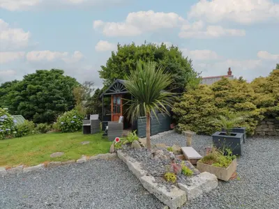 a small house with a palm tree in a garden at Cuckoo's Rest in Penryn